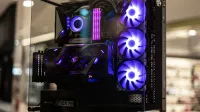 Modern gaming computer with vibrant LED fans and sleek glass design, showcasing high-performance components.