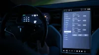 Vista interior de un automóvil eléctrico que muestra la pantalla táctil avanzada y el volante por la noche.