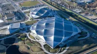 Una foto aérea de tres grandes marquesinas que están cubiertas de paneles solares.