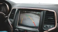 Primer plano del tablero de un automóvil que muestra una pantalla de cámara de retrovisor para la asistencia de estacionamiento.