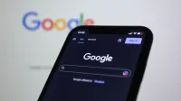 Pantalla de teléfono inteligente que muestra la búsqueda de Google en modo oscuro con el logotipo de Google en segundo plano.
