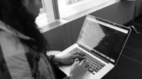 Una mujer escribiendo un código en una computadora portátil en un entorno interior moderno, mostrando el trabajo tecnológico.