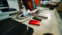 Un escritorio de oficina cuidadosamente organizado con una computadora portátil y varios discos duros externos, perfecto para un espacio de trabajo digital.