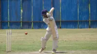 Jugador de críquet en acción, bateando en un campo de hierba en Gahunje, India.