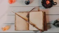 Abra el libro de hechizos con varita mágica y botellas de poción en una mesa de madera, evocando un tema mágico místico.