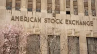 Facade of the American Stock Exchange Building in New York City during spring with blooming trees.