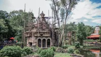 Scenic view of an ancient-looking temple surrounded by lush greenery in a theme park setting.