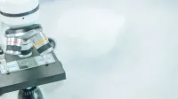 Primer plano detallado de un microscopio en un laboratorio con enfoque superficial resaltando sus componentes.