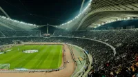A crowded soccer stadium under bright lights at night, capturing the excitement of a live sports event.