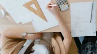 An overhead view of a student studying geometry using a calculator and notes at home. Perfect for education visuals.