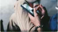 Una vista de cerca de una persona que usa un teléfono inteligente en interiores, mostrando la tecnología moderna.