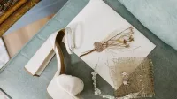Tacón alto blanco y accesorios delicados en una silla vintage, perfecto para un tema nupcial.