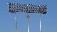 Tall stadium floodlights towering against a clear blue sky, perfect for outdoor sports lighting visuals.
