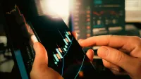 Manos interactuando con gráficos financieros en un teléfono inteligente, mostrando las tendencias del mercado de valores.