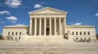 The majestic facade of the United States Supreme Court under a clear blue sky.