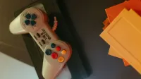 Un controlador de juego vintage de 8 bits con botones de colores junto a cartuchos de juegos clásicos.