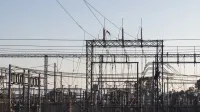 High-voltage electrical substation with steel structures and power lines at dawn.