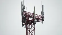 A red communication tower with antennas stands tall against a gray sky.