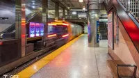 Coche de línea naranja se acelera fuera de la estación con plataforma en el lado derecho