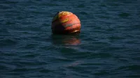 Fotografía de una boya roja que se balancea en la superficie del océano durante el día, capturando temas náuticos.