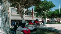 Una escena sincera de gente relajándose a la sombra de un parque en Pacasmayo, Perú, capturando la vida cotidiana.