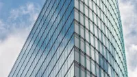 A sleek glass skyscraper reflecting the blue sky and clouds, showcasing modern architectural design.