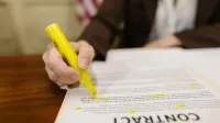 Un primer plano de una mano que destaca un contrato, enfatizando importantes términos legales.