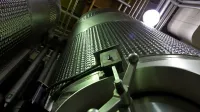 Low-angle shot of large stainless steel tanks inside a modern industrial facility.