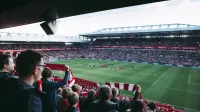 Fans cheer as players take the field at a vibrant football stadium, creating an electric atmosphere.