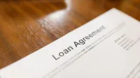Detailed loan agreement document close-up on a wooden table representing legal and financial concepts.
