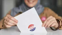 Close-up of hands holding a vote ballot, symbolizing election participation.