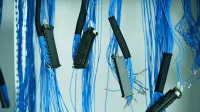 Close-up de cables Ethernet azules colgados en un centro de datos, destacando las conexiones tecnológicas.