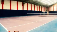 Empty indoor tennis court with rackets and balls in the foreground, showcasing a sports arena setup.