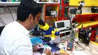 A technician skillfully repairs a PCB using a microscope in a modern electronics lab.