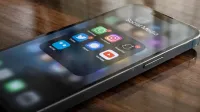 Close-up de smartphone en mesa mostrando varios iconos de aplicaciones de redes sociales incluyendo WhatsApp e Instagram.