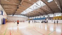 Vista de gran angular de una cancha de baloncesto cubierta con jugadores practicando y participando en actividades deportivas.