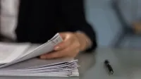 Close-up of a professional organizing a stack of documents on a desk.