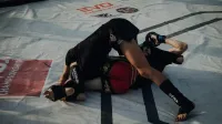 Mixed martial arts fighters in an intense grappling competition in an arena.