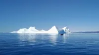 Una serena escena de un iceberg con un pequeño bote en las aguas de Ilulissat, Groenlandia.