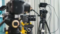Close-up de cámaras de video de alta gama y trípodes en un estudio moderno.