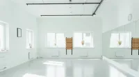 Estudio de baile brillante y vacío con espejos y luz solar en streaming.