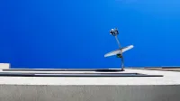 Vista de ángulo bajo de una antena parabólica en un edificio moderno contra un cielo azul claro.