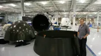 Varios componentes de la cápsula SpaceX Dragon en un estado de desmontaje, con Elon Musk esperando.