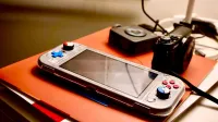 A portable gaming console beside a digital camera showcases modern entertainment and technology setup.