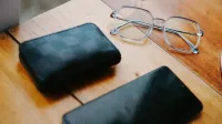 Stylish eyeglasses, wallet, and smartphone on a wooden table. Elegant composition.