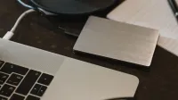 Primer plano de un disco duro externo conectado a una computadora portátil con un cable USB en un escritorio.
