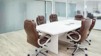 Amplia sala de conferencias con diseño moderno, con sillas de cuero y una mesa blanca.