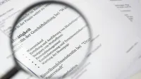 Primer plano de un texto de documento de negocios bajo una lupa.