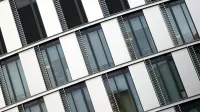 Vista en ángulo de un moderno edificio de oficinas con grandes ventanas de vidrio y detalles de acero.