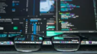 Gafas que reflejan el código de la computadora en un monitor, ideal para la tecnología y los temas de programación.